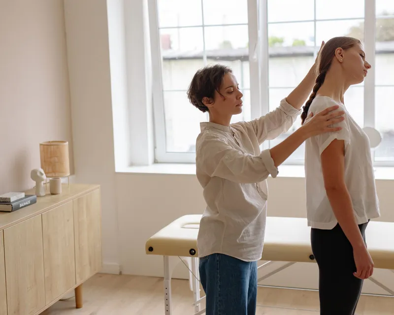 Practitioner checking a young woman’s standing posture