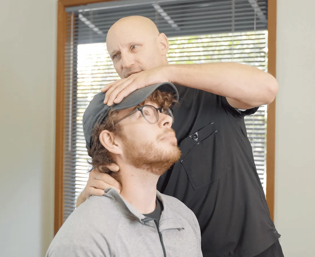 Dr. Ryan Woodbury checking a patient’s neck during an exam at Pinnacle Chiropractic in Arlington